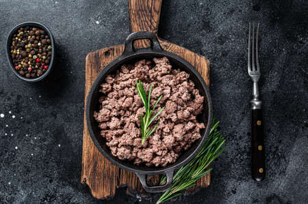 Fried mince beef meat in a pan for cooking pasta. Black background. Top view