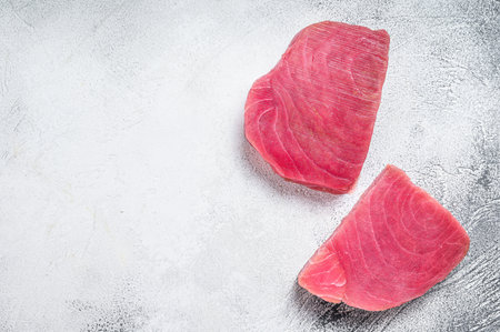 Two raw tuna steaks on rustic table. White background. Top view. Copy spaceの写真素材