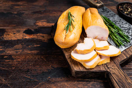 Sliced Smoked chicken breast fillet meat on a butcher board. Dark wooden background. Top view. Copy spaceの写真素材