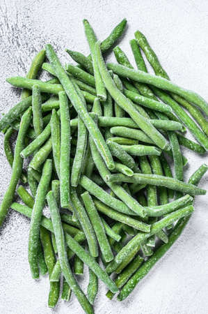 Frozen green beans on the white kitchen table. White background. top view