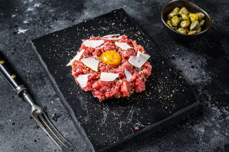 Tartar beef with a quail egg, capers and Parmesan cheese. Black background. Top viewの写真素材