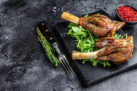 Stew Lamb Shanks on a marble board with arugula. Black background. Top view. Copy spaceの写真素材