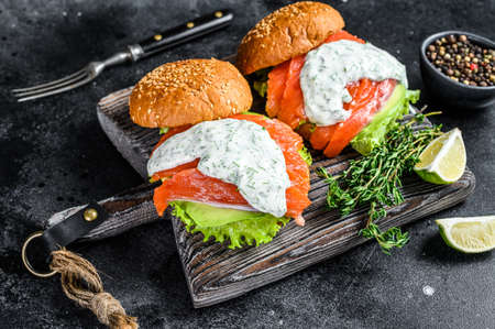 Fish burger with salted salmon, avocado, mustard sauce, cucumber and Iceberg salad. Black background. top viewの写真素材