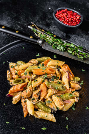 Italian Color Penne pasta with mussels on a plate. Black background. Top viewの写真素材