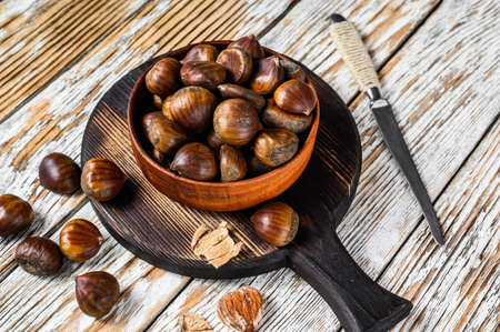 Bowl with chestnuts on a wooden table. White background. Top viewの写真素材