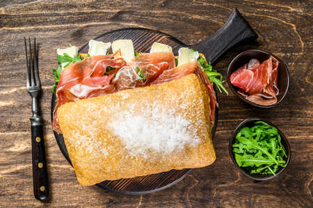 Jamon Ham Sandwich on ciabatta bread with arugula and camembert brie cheese. wooden background. Top viewの写真素材