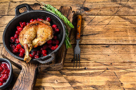 Fried duck leg with cranberrie sauce in a pan. wooden background. top view. Copy spaceの写真素材