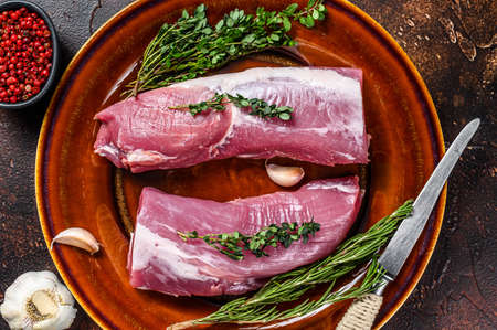 Fresh pork tenderloin meat with rosemary and thyme. Dark background. Top viewの写真素材