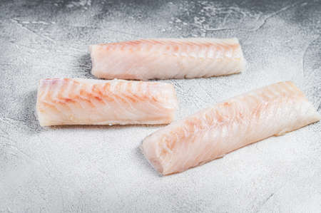 Raw Norwegian cod fish fillet on kitchen table. White background. Top view