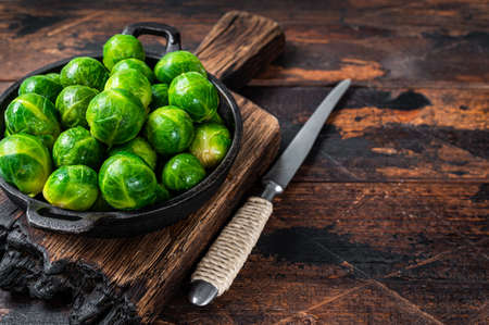 Boiled Brussels green sprouts cabbage in a pan. Dark wooden background. Top view. Copy space