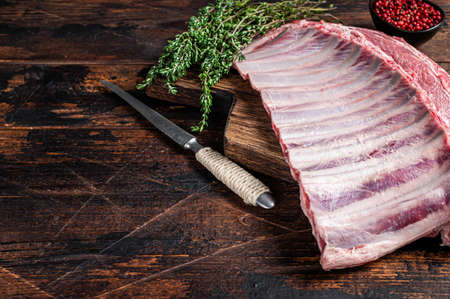 Mutton lamb ribs rack on wooden cutting board. Dark wooden background. Top view. Copy spaceの写真素材