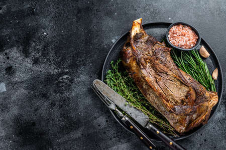 Roasted lamb mutton shoulder meat on a plate with knife and fork. Black background. Top view. Copy spaceの写真素材