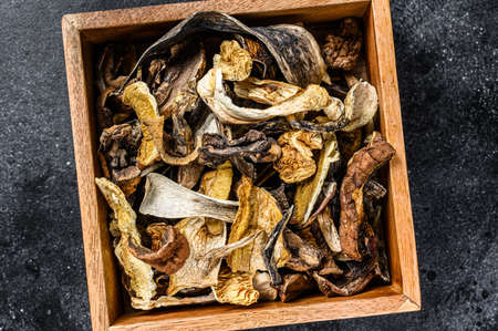 Boletus wild dried mushrooms in a wooden box. Black background. Top viewの写真素材