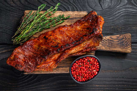 Grilled in bbq sauce veal short spare rib meat on wooden cutting board. Black wooden background. Top viewの写真素材