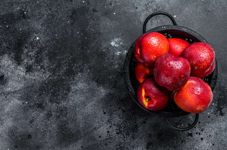 Red organic nectarines in a colander. Black background. Top view. Copy spaceの写真素材