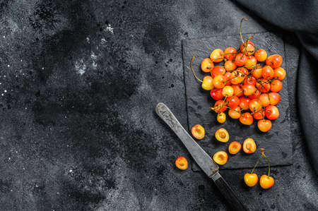 Yellow ripe cherries on a black plate. Black background. Top view. Copy spaceの写真素材