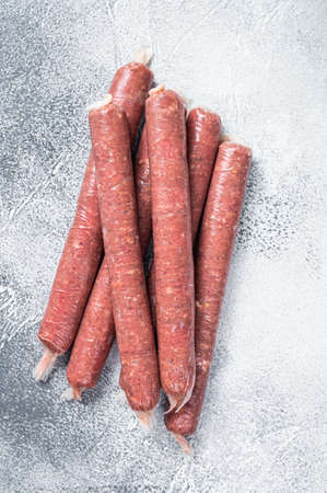 Raw butchers sausages in skins with herbs on kitchen table. White background. Top viewの写真素材