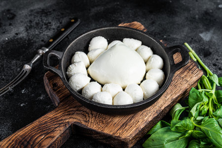 Mozzarella cheese mini balls in pan with basil. Black background. Top viewの写真素材