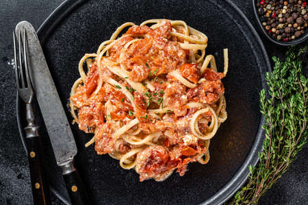 Trendy Feta pasta with Oven baked cherry tomatoes and cheese on a plate. Black background. Top viewの写真素材