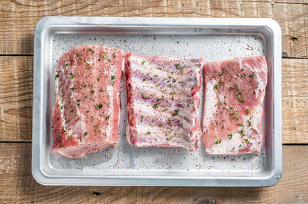 Set of Raw pork cuts, loin meat, spare ribs and brisket. Wooden background. Top view