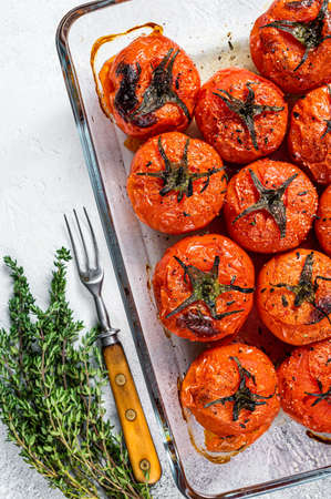 Roasted tomatoes with olive oil and thyme in baking dish. White background. Top viewの写真素材