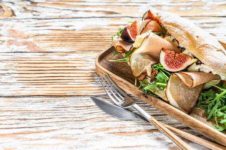 Sandwich with arugula, fig, prosciutto, Ciabatta and blue cheese on a wooden tray. White background. Top view. Copy spaceの写真素材