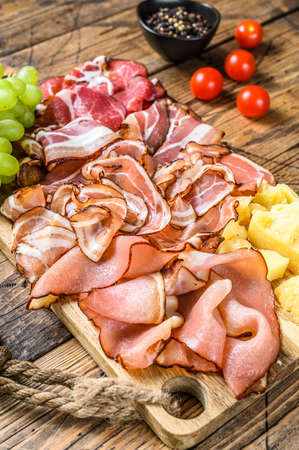 Set of cold cured italian meat Ham, prosciutto, pancetta, bacon with parmesan and grape. wooden background. Top viewの写真素材