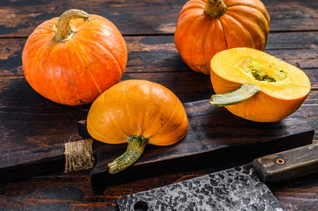 Slicing raw orange pumpkin. Dark wooden background. Top viewの写真素材