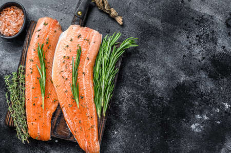 Salted salmon or trout sea fish fillet with spices and herbs. Black wooden background. Top view. Copy spaceの写真素材