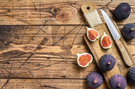 Sliced purple figs on a cutting Board. Wooden background. Top view. Copy spaceの写真素材