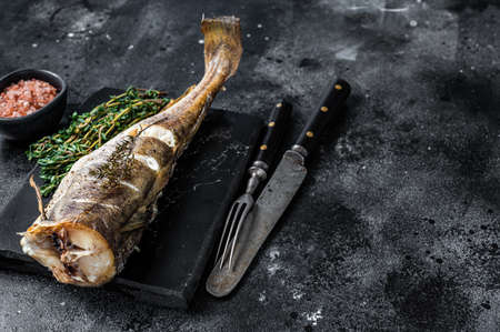 Roasted cod white fish with thyme on marble board. Black background. Top view. Copy space