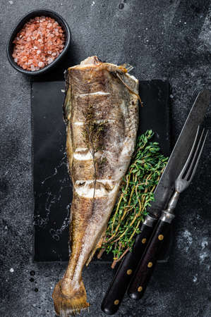 Roasted cod white fish with thyme on marble board. Black background. Top view