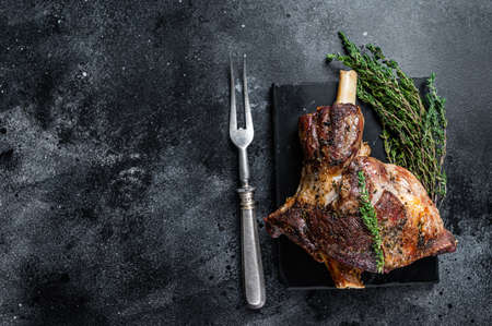Oven Roasted lamb mutton whole leg with thyme. Black background. Top view. Copy spaceの写真素材
