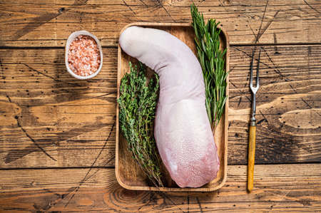 Raw pork tongue on butcher tray with meat knife. wooden background. Top viewの写真素材