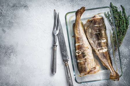 Fish dish - roasted cod fish with herbs in baking dish. White background. Top view. Copy spaceの写真素材
