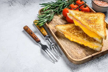 Homemade fried ham and cheese sandwich on a cutting board. White background. Top view. Copy spaceの写真素材