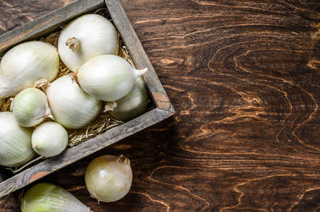 Raw fresh white onion in wooden box. Wooden background. Top view. Copy spaceの写真素材