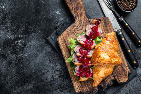 Croissant sandwich with Duck breast steak slices, arugula and sauce. Black background. Top View. Copy spaceの写真素材