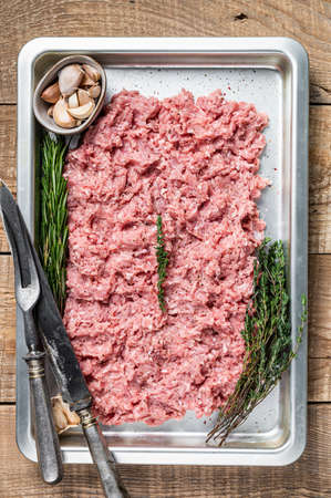 Turkey or chicken mince raw meat in a kitchen tray. Wooden background. Top View
