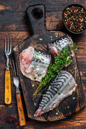 Cut smoked mackerel fish with herbs. Dark wooden background. Top viewの写真素材