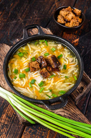 Chicken soup with noodles and vegetables. Dark wooden background. Top viewの写真素材