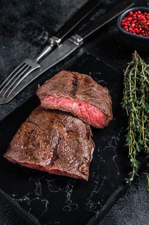 Grilled Top Blade or flat iron roast beef meat steaks on marble board. Black background. Top Viewの写真素材