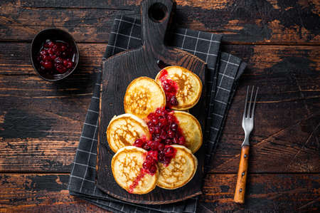 Stack of cranberry syrup pancakes on wooden board. Dark wooden background. Top View