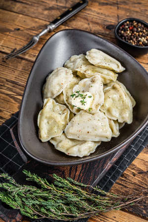 Dumplings pierogi with potato in a plate with herbs and butter. Wooden background. Top Viewの写真素材