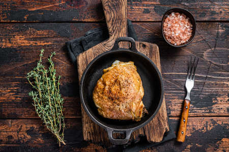 Baked chicken thigh in a pan with rosemary and salt. Dark wooden background. Top Viewの写真素材