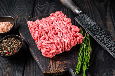 Raw mince lamb, ground meat with herbs and spices on a wooden cutting board. Black wooden background. Top viewの写真素材