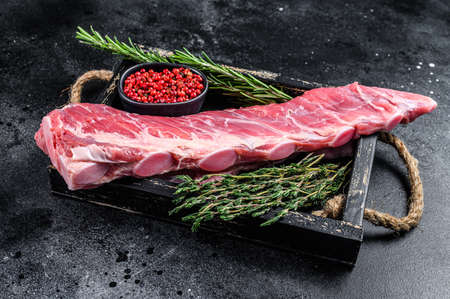 Raw veal calf short spare rib meat with thyme and rosemary. Black background. Top view