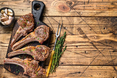 Grilled lamb mutton meat chops steaks on a cutting board. wooden background. Top view. Copy space