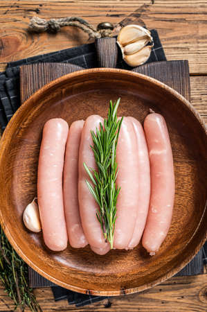 Poultry raw sausages in a wooden palte with herbs. wooden background. Top viewの写真素材