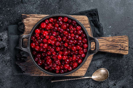 Red fresh Cranberry berry in a pan. Black background. Top view